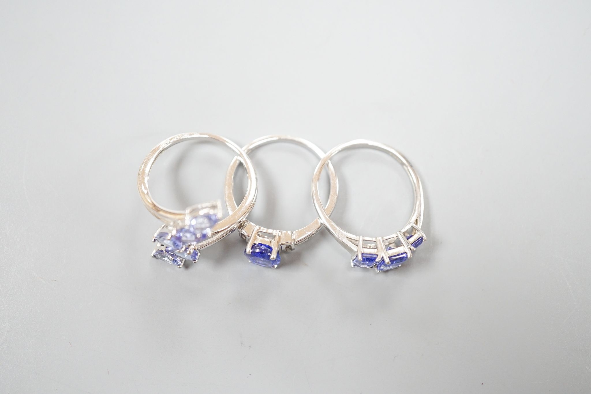 Three assorted modern 9ct white gold and tanzanite set dress rings, gross weight 8.6 grams.